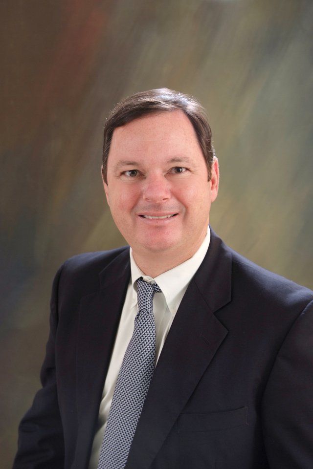 A man in a suit and tie is smiling for the camera.